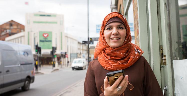 woman standing in the street holding a mobile phone