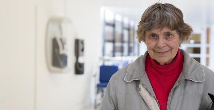 older person standing in hospital corridor