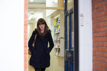 Woman walking out of a GP surgery with a neutral expression