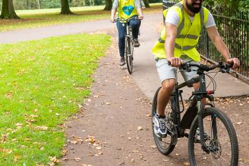 Front cover of Healthwatch Liverpool Annual Report 2020-21 - two cyclists ride through Sefton Park